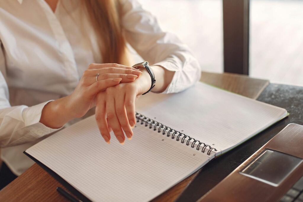 Faceless crop female entrepreneur checking time while working with papers